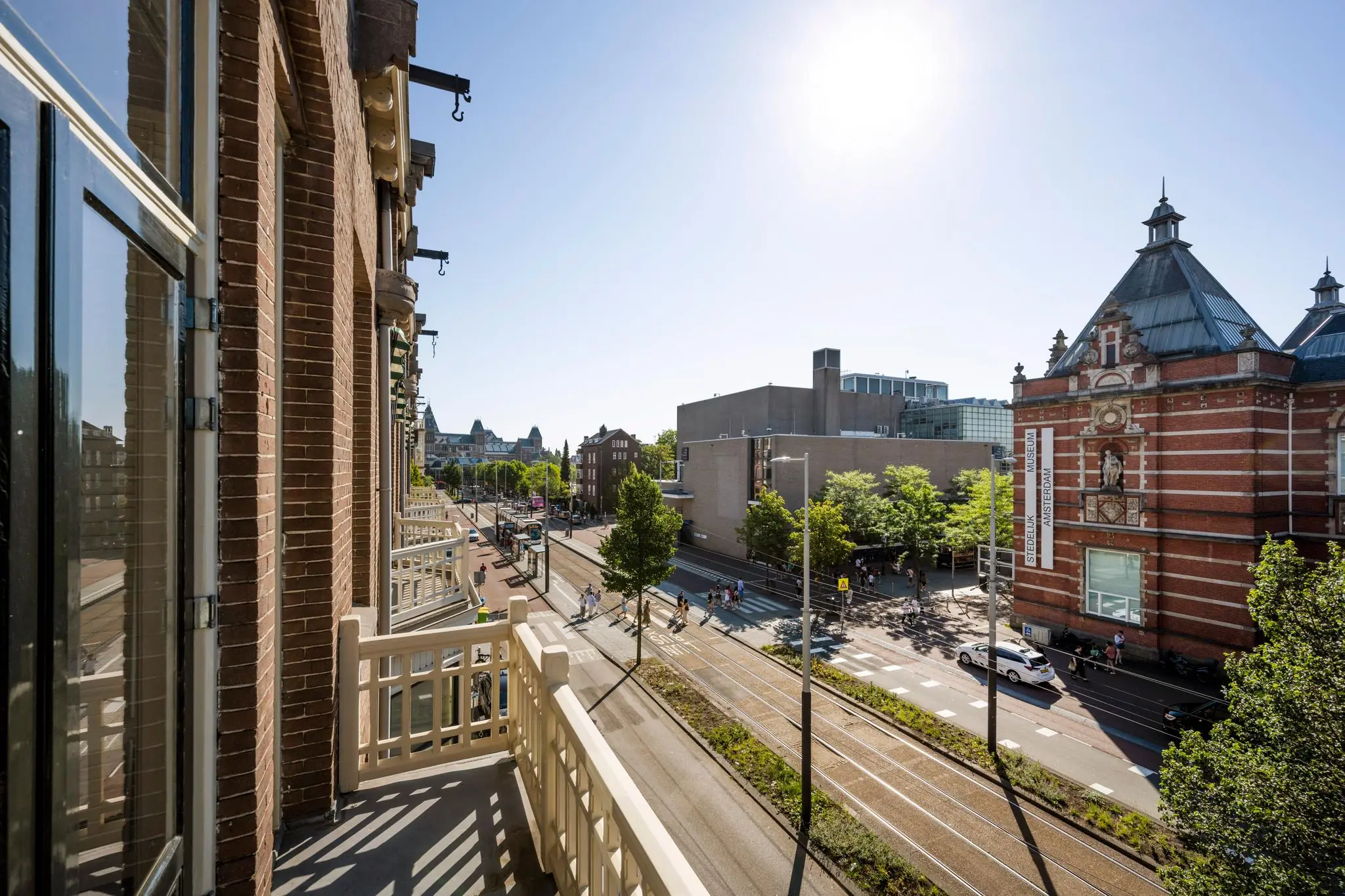 Uitzicht vanaf een balkon op de Paulus Potterstraat in Amsterdam met zicht op het Stedelijk Museum en voorbijrijdende trams.